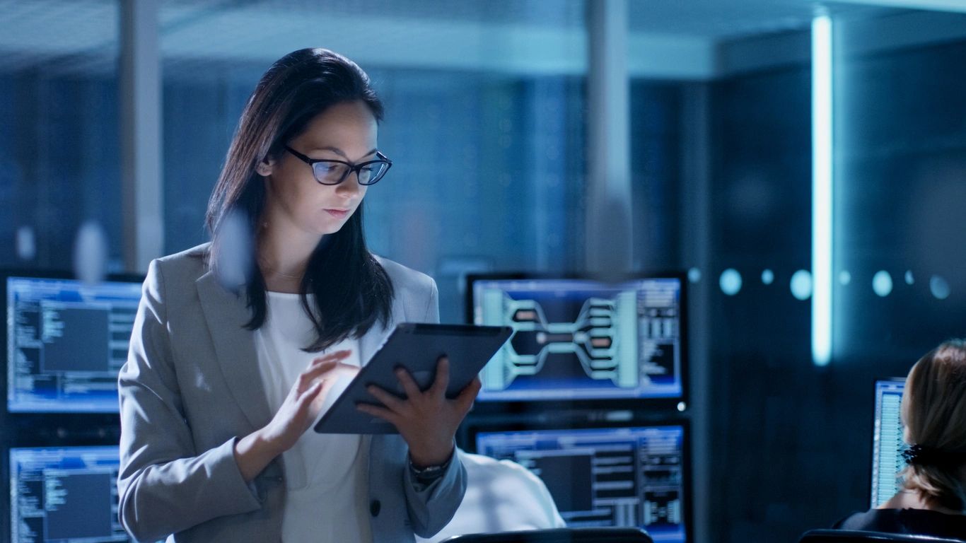 A woman in glasses is looking at her tablet.